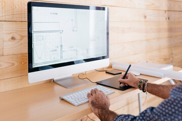 Close-up of man working on floor plan at home using the computer and graphics tablet