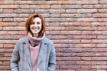 Portrait of a happy young woman standing at a brick wall