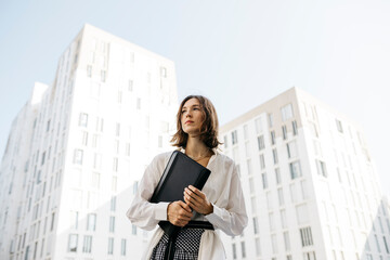 Serious woman carryiing folder in the city