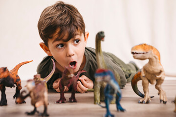 Portrait of little boy playing with toy dinosaurs