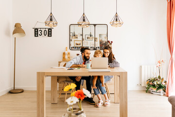 Parents with daughter using laptop on dining table at home