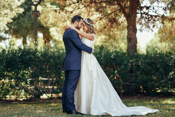 Bridal couple standing head to head with eyes closed in a park