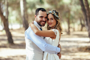 Portrait of happy bridal couple standing head to head in pine forest