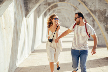 Spain, Andalusia, Malaga, carefree tourist couple running under an archway in the city