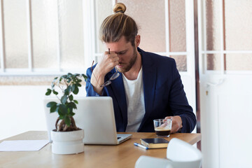 Tired businessman sitting at table in office