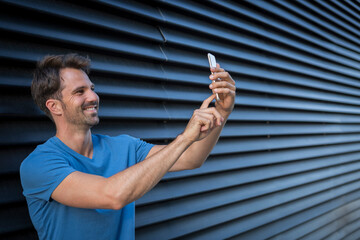 Man standing in front of roller shutter, taking a selfie