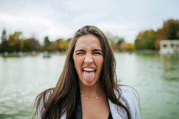 Portrait of woman at a lake sticking out her tongue