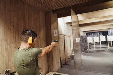 Man aiming with a pistol in an indoor shooting range