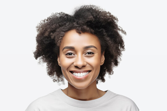 Studio portrait of a beautiful middle age woman with black curly hair. Laughing woman wearing white t-shirt looking at camera. Isolated on grey background. People, lifestyle, beauty concept