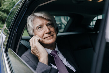 Portrait of pensive senior businessman looking through car window
