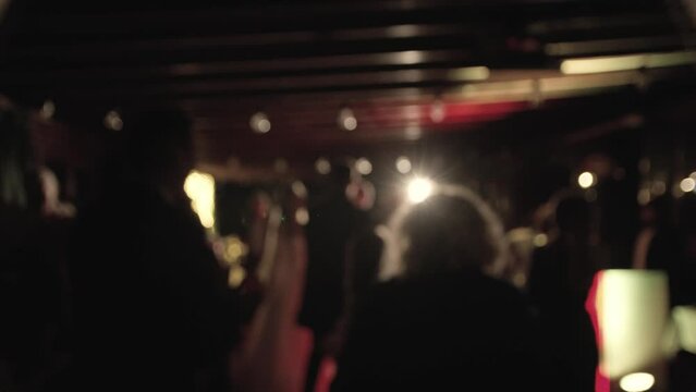 Defocused view of great wedding party with silhouettes of people dancing on the dancefloor. Slow motion.
