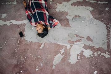 Woman lying on cracked floor with cell phone