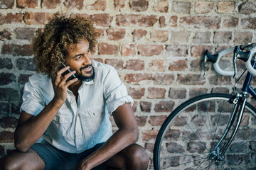 Smiling young man with bicycle on cell phone