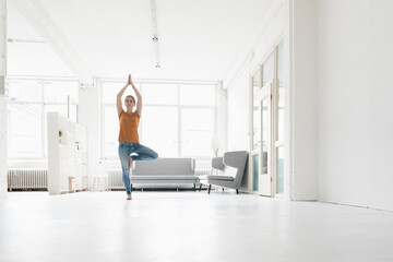 Woman practising yoga in a loft