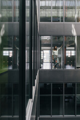 Woman standing at office window, looking up