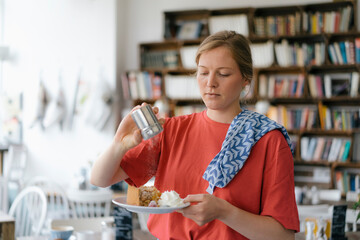 Young woman serving plate with cake in a cafe