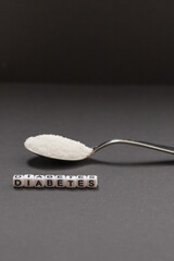 White crystal sugar on a small spoon with the inscription diabetes..Campaign to reduce sugar consumption.