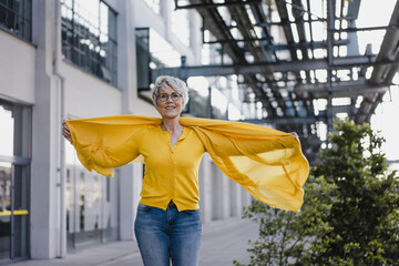 Portrait of smiling mature woman wearing yellow cardigan and scarf