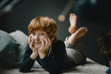 Portrait of smiling redheaded boy lying on couch at home © tunedin