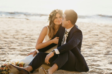 Happy bridal couple sitting at the beach