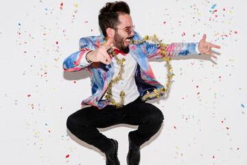 Stylish man wearing a colorful suit and sunglasses celebrating a party and jumping