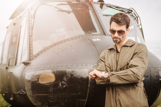 Man in overall next to a helicopter checking the time