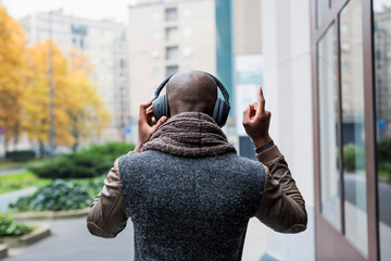 Back view of bald man listening music with headphones