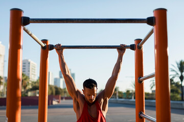 Fit man working out in climbing parcour, doing pull ups