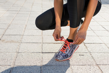 Close-up of young woman tying her shoes before workout