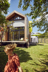 Mother with daughter standing on grassy land in yard outside tiny house