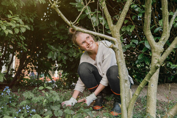 Smiling young woman clearing weeds in the garden © tunedin