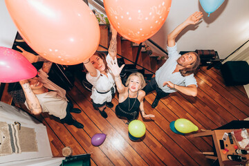 Cheerful friends dancing with colorful balloons during party at home