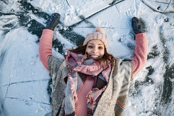 Portrait of happy woman lying down on frozen lake surface