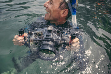 Happy man with underwater DSLR camera case in a lake