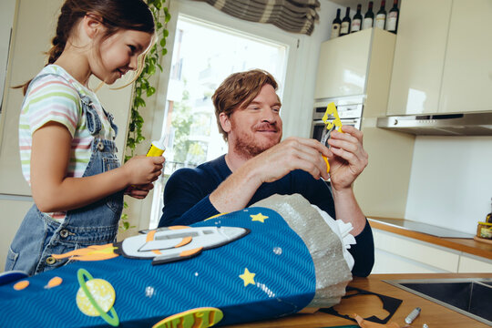 Father and daughter creating her space themed school cone at home