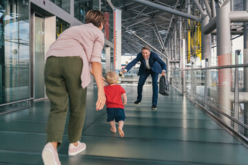Happy child running into arms of travelling businessman at the airport