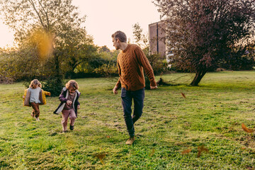 Naklejka na ściany i meble Father running with daughters on a meadow in autumn