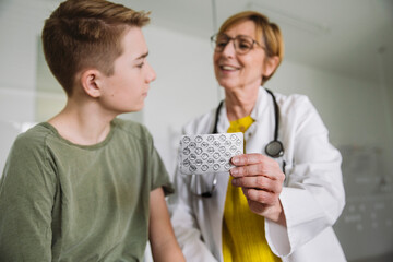 Doctor explaining medication to teenage boy in medical practice