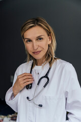 Portrait of doctor with stethoscope against grey background