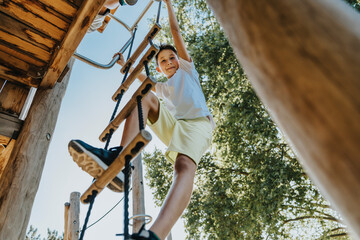 Boy climbing ladder in public park on sunny day