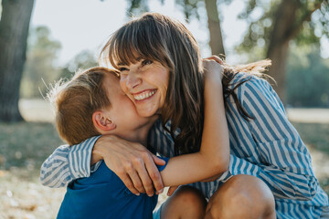 Smiling mother embracing son in public park