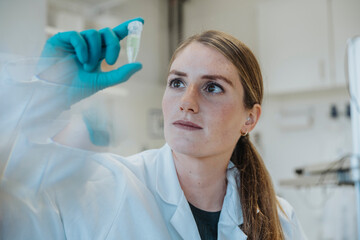 Young woman examining test tube while standing at laboratory