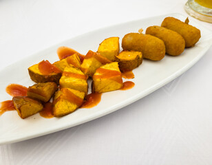 Baked potatoes with croquettes and ketchup are on a plate