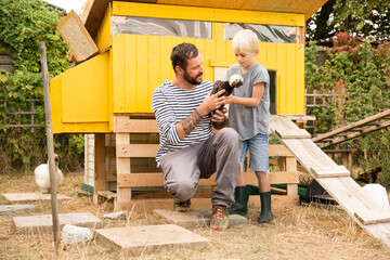 Father and son with Polish chickens at chickenhouse in garden
