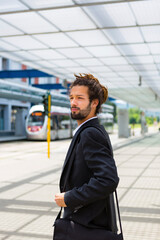 Portrait of young businessman with dreadlocks waiting at station