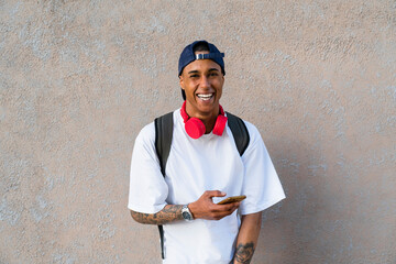 Portrait of tattooed young man with smartphone and red headphones