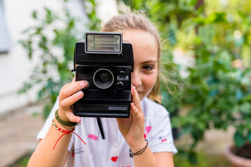 Girl taking a picture with an old-fashioned camera outdoors