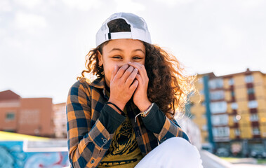 Portrait of laughing girl covering mouth with her hands