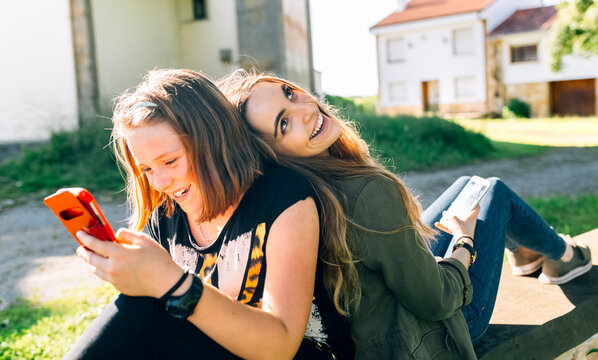 Two happy girls using their smartphones outdoors