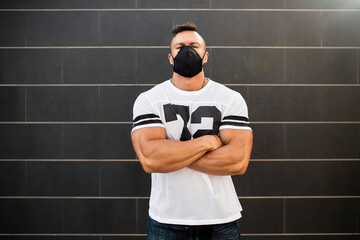 Macho young man wearing face mask standing against wall